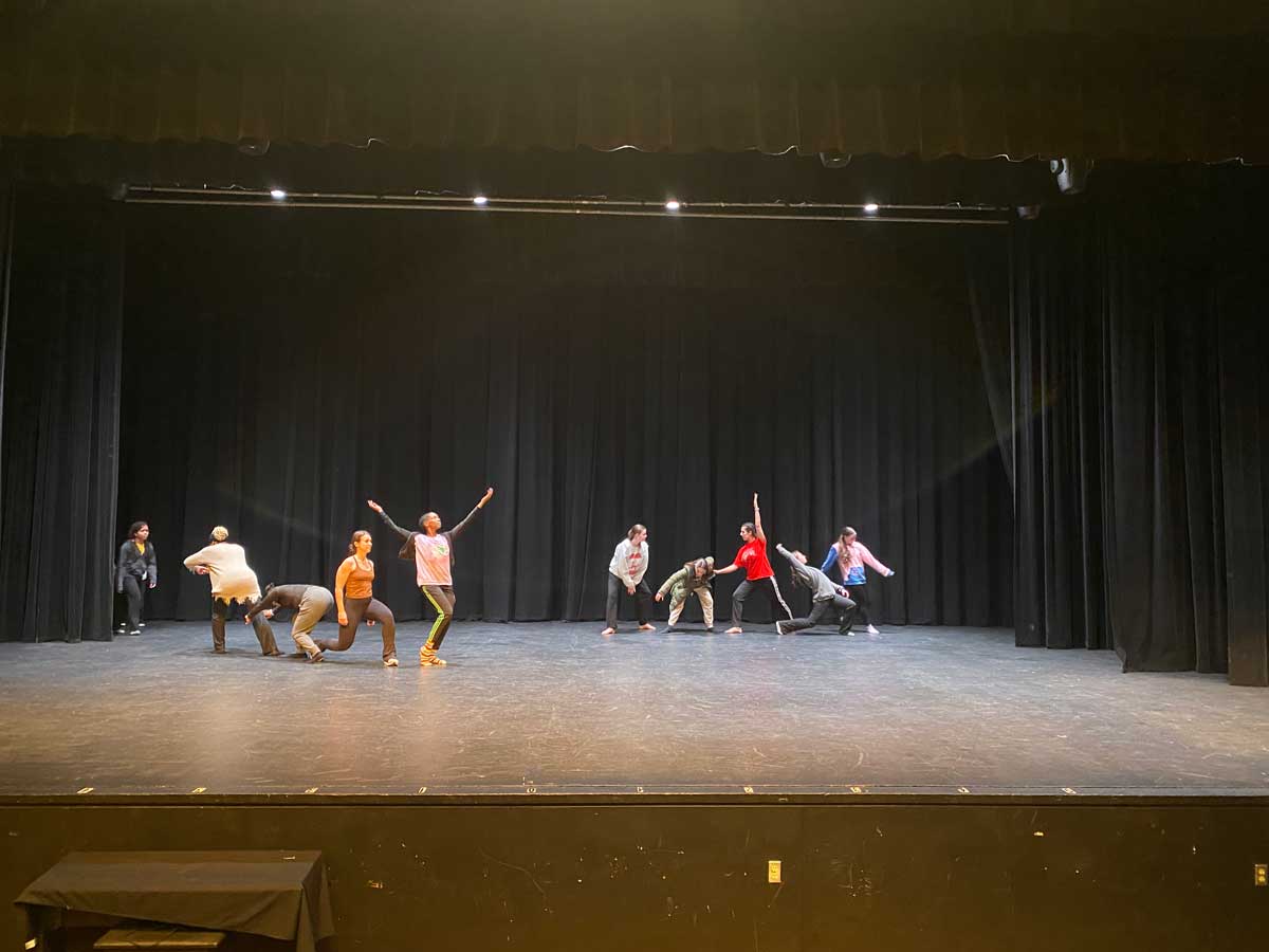 two groups of five students practicing various movements on stage